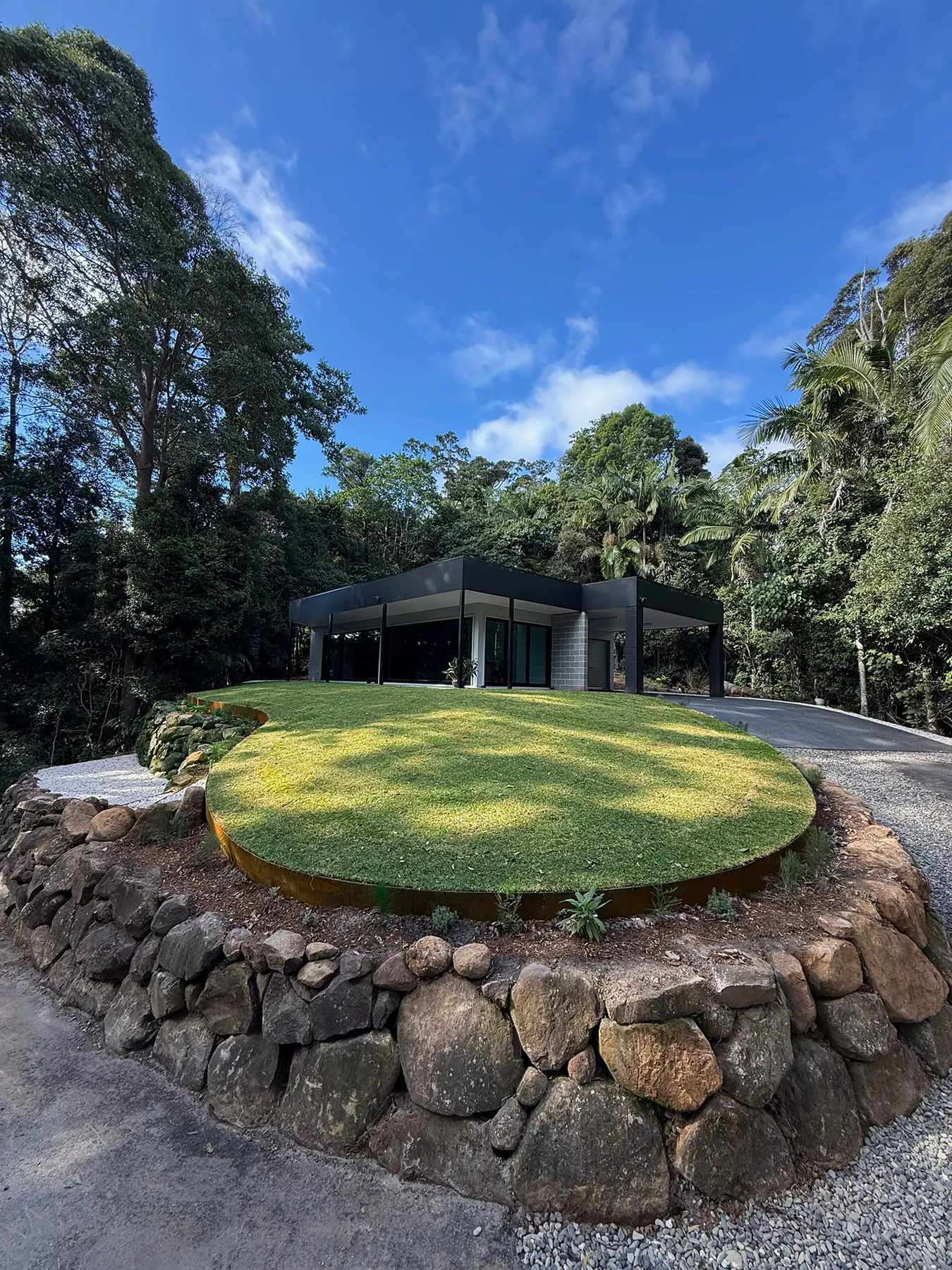 Raised circular lawn on a dry stone wall in front of a dark pavilion