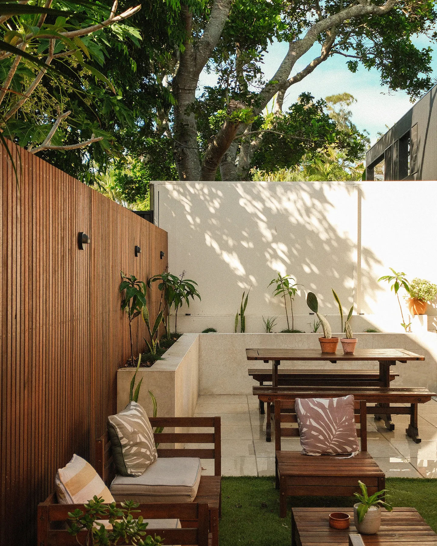 Walled courtyard dining nook with timber screen and rendered planter
